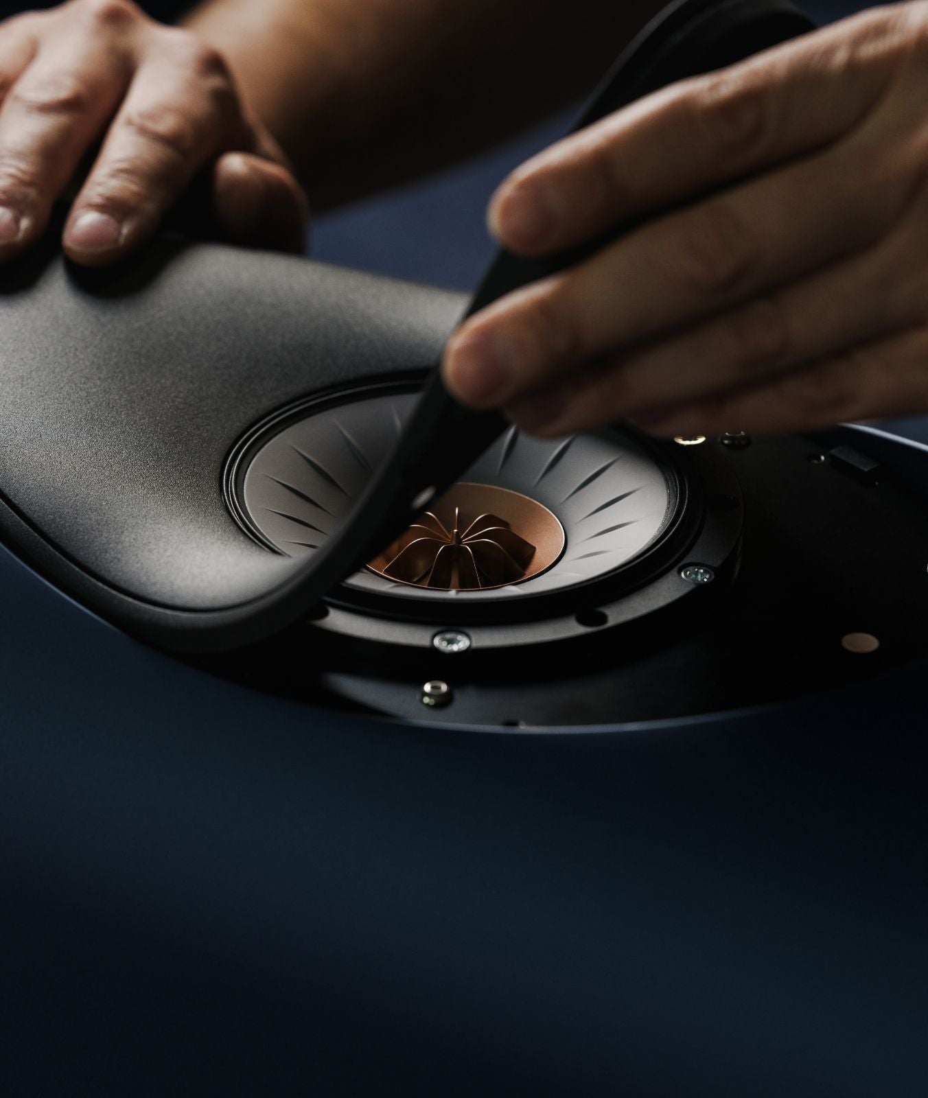 Close-up of a person building a KEF Blade speaker by hand.