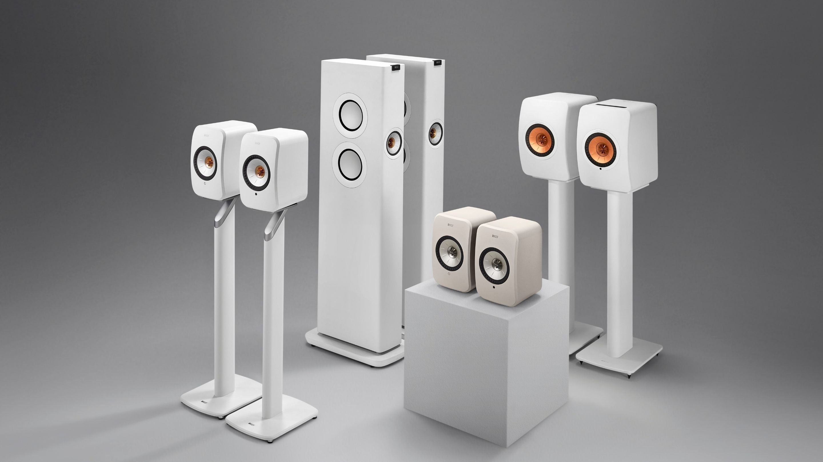 Set of white speakers on stands against a gray background