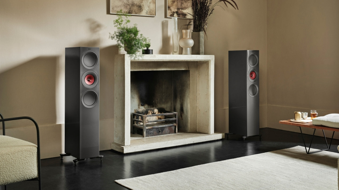 Pair of black R Series floorstanding speakers in living room with fireplace.